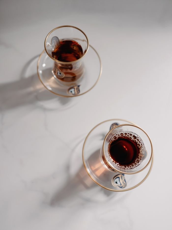 Aerial view of two Turkish teas served in traditional glass cups on a white surface.